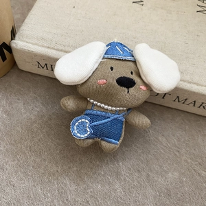Detail of a handmade knitted puppy plush hair clip with denim outfit and pearl necklace
