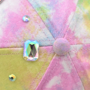 Macro detail of tie-dye baseball cap featuring colorful gemstones and precision stitching