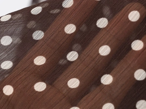 Detailed macro shot of brown woven fabric featuring white polka dot patterns