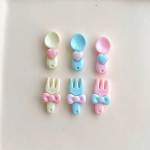 Miniature resin cutlery set with heart and bow details in pastel pink, blue, and beige