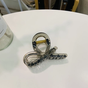 Minimalist translucent smoke grey hair claw clip with golden spring on white surface