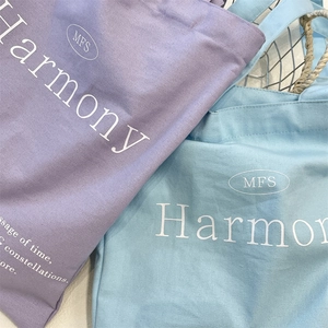 Close-up of canvas tote bag texture with MFS Harmony logo print in purple and blue
