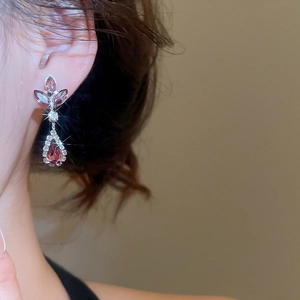 Close-up of pink gem and zircon earrings in floral leaf design worn by a model