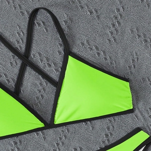 Detail of neon green bikini top with black contrast binding and criss-cross strap design