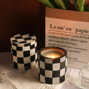 Candela profumata a scacchi e barattolo con coperchio coordinato su un tavolo accogliente