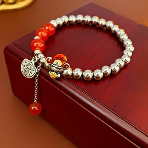 Detail of beaded dragon bracelet with silver beads, red agate, and Fu character pendant
