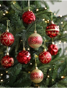 Detail of red and gold Christmas balls with snowflake patterns on a tree with warm lights