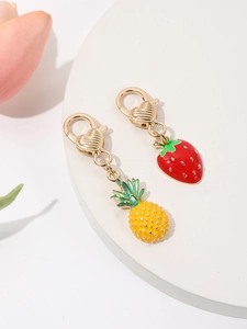 Close-up of enamel pineapple and strawberry pendants with heart lobster clasps on white stand