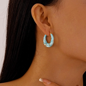 Detail of blue marble resin hoop earring with gold metal accent and sparkling rhinestone