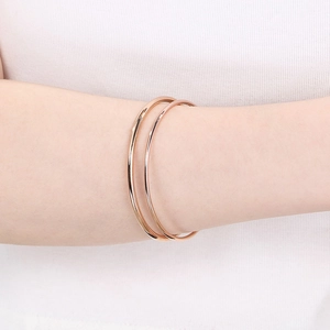 Detail shot of 18k rose gold plated titanium steel bangles on a female wrist