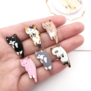 Set of six colorful alloy cat charms in various patterns held in a palm for scale