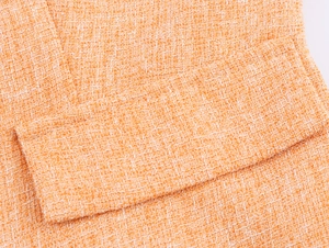 Vue macro détaillée montrant la texture tissée orange du tissu en tweed de l'ensemble