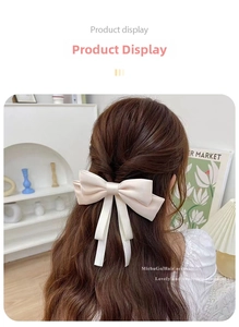 Detail of cream silk satin bow hair clip with long ribbons on a model's hairstyle