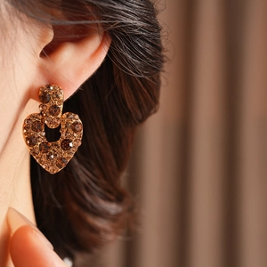 Gros plan de boucles d'oreilles vintage en cœur avec cristaux ambrés sur un modèle