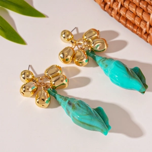 Detailed view of turquoise conch resin earrings with golden metal cluster details