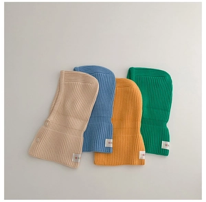 Flat lay of ribbed knit baby balaclava hats in beige blue yellow and green colors