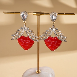 Macro view of gold wheat earrings with red resin hearts and sparkling crystal wings