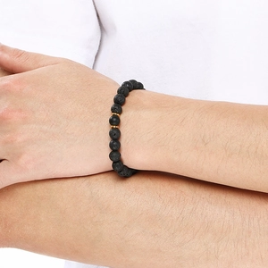 Mens 8mm black lava stone and agate beaded bracelet with gold accents worn on wrist