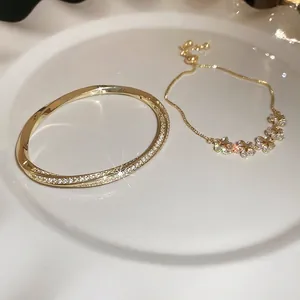 Gold plated bracelet and bangle set with star-flower zircon charms on ceramic plate