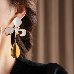 Detail von Vintage-Blumenohrringen in Weiß mit goldenem Tropfenanhänger am Model