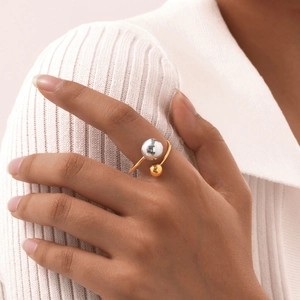 Detail of adjustable gold and silver bead open ring worn on finger with a minimalist style