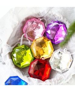 Close-up of colorful faceted diamond ornaments in assorted colors on white background