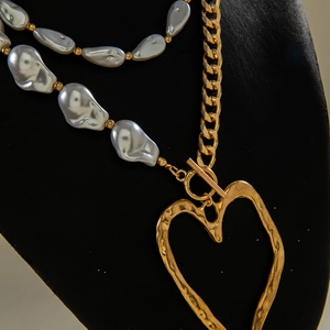 Detail of multi-layer necklace with irregular pearls and hammered gold heart pendant