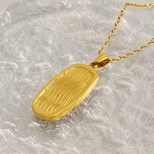 Detailed close-up of golden wavy rectangular pendant with elegant textured finish