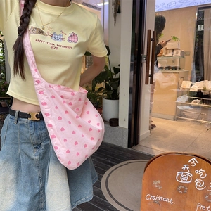 Detailed view of a pink heart-patterned canvas tote bag styled with a casual summer outfit