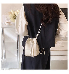 Detail of white hand-woven bucket bag with drawstring closure and knotted strap detail