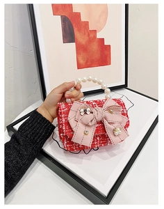 Detail of red tweed girl's bag with pink ribbon bow and white faux pearl handle