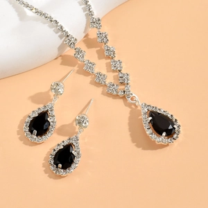 Close-up of silver jewelry set with black pear-shaped stones and shimmering zircon