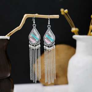 Detailed shot of bohemian tassel earrings with colorful beads hanging on a rustic branch