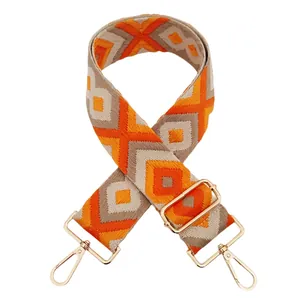 Detail of embroidered geometric bag strap with golden metal hooks in yellow orange khaki