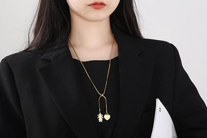 Adjustable gold snake chain necklace featuring heart and girl silhouette charms worn by model
