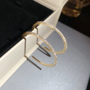 Close-up of golden C-shaped hoop earrings with shimmering crystals on jewelry box display