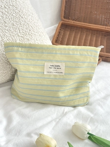Detailed macro view of striped canvas toiletry bag with textile label and zipper closure