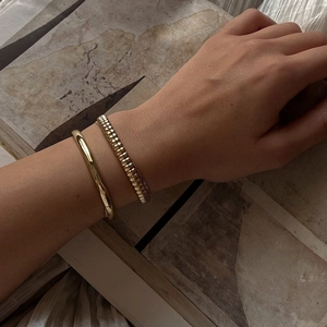 Elegant 18K gold-plated stainless steel bracelet set styled on model with artful background
