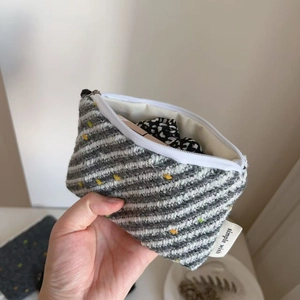 Dettaglio della piccola borsa in lana a righe grigie e bianche con pois gialli