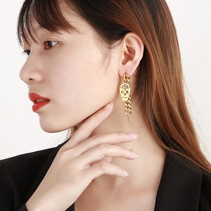 Punk style golden stainless steel skull drop earrings with curb chain on female model