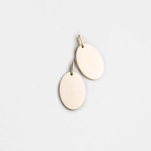 Close-up of two polished oval gold stainless steel pendants with rings for DIY jewelry