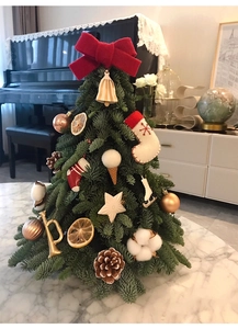 Mini Christmas tree with red bows, pine cones, and bells on a marble tabletop