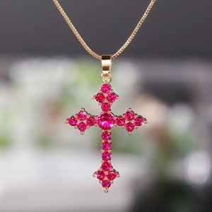 Detailed macro view of a golden cross pendant featuring brilliant pink crystal gemstones