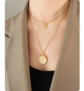 Detail of gold double-layered necklace with star charm and circular locket on a model