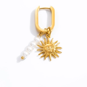 Detail of gold U-shaped earrings with hanging pearls and embossed sun charms