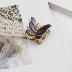 Macro detail of golden butterfly hair claw clip with purple iridescent enamel wings