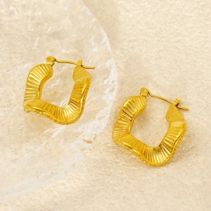 Textured gold wavy rectangle earrings in stainless steel on sand base backdrop