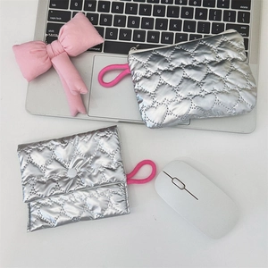 Silver quilted heart pouch and flap bag set with pink loops on a white tech desk