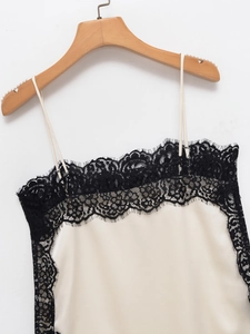 Close-up of cream satin camisole featuring delicate black floral lace trim on hanger