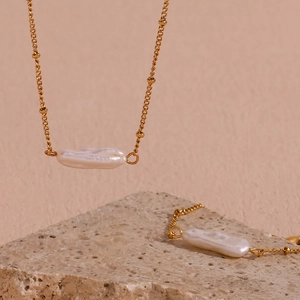 Detail of 18K gold plated bead chain with natural white baroque pearl pendant on stone